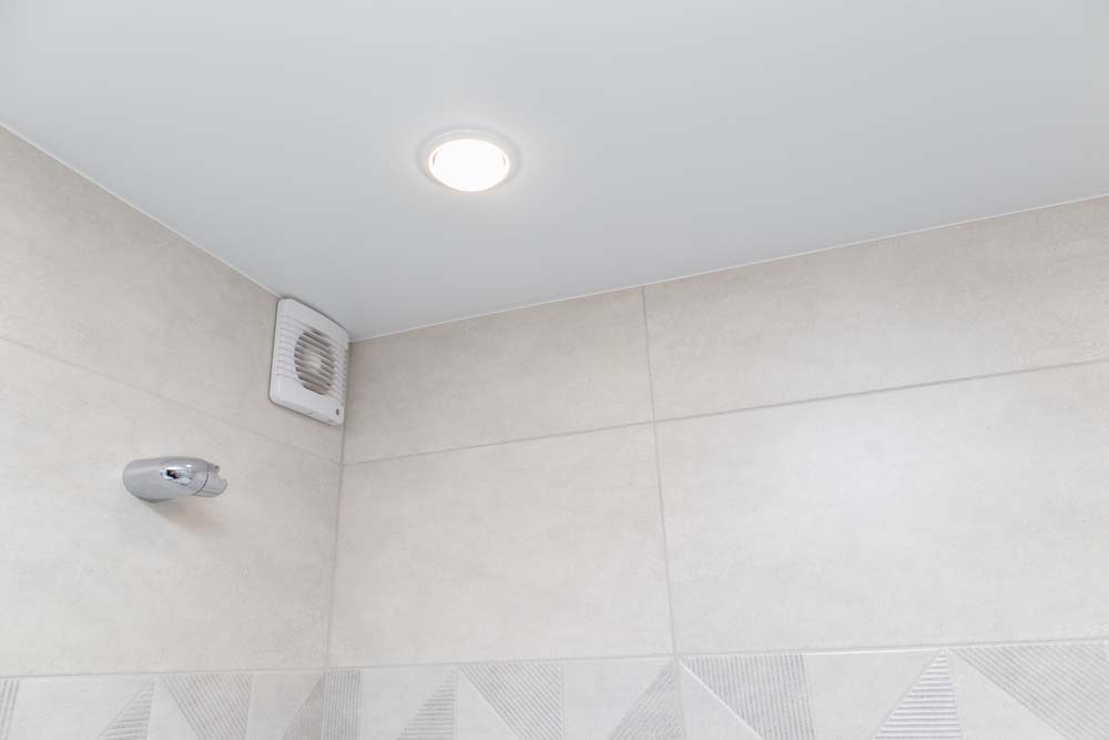 an exhaust fan in a bathroom above a shower door
